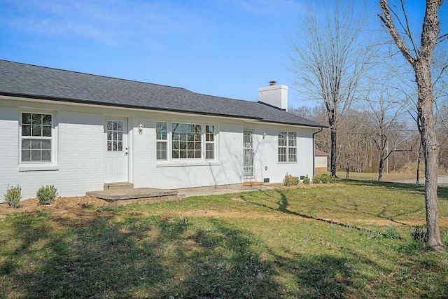 ranch-style house with a shingled roof, a front lawn, brick siding, and a chimney