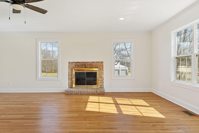 unfurnished living room with baseboards, a brick fireplace, a healthy amount of sunlight, and light wood-style flooring