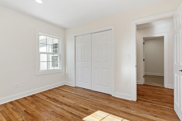 unfurnished bedroom with baseboards, light wood-type flooring, and a closet