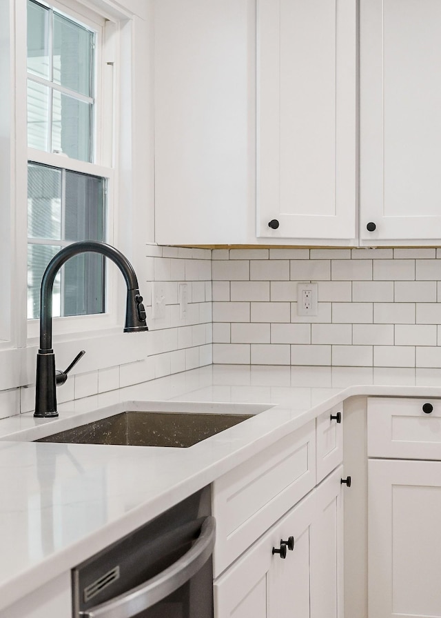 kitchen with a sink, white cabinetry, light countertops, decorative backsplash, and dishwasher