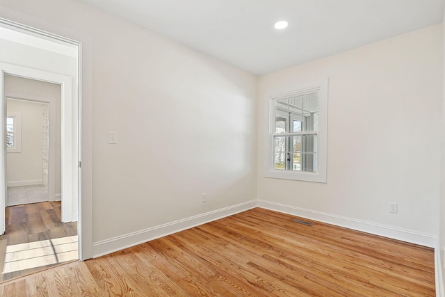 unfurnished room featuring visible vents, light wood-style flooring, baseboards, and a healthy amount of sunlight