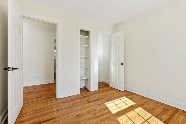 unfurnished bedroom with a closet, light wood-style flooring, and baseboards