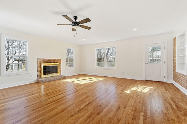 unfurnished living room featuring light wood finished floors, a healthy amount of sunlight, baseboards, and a ceiling fan