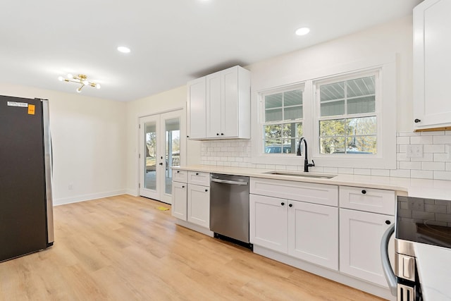 kitchen with a sink, stainless steel appliances, light wood-type flooring, and decorative backsplash