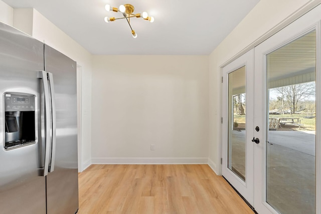 entryway with a notable chandelier, french doors, baseboards, and light wood-style floors