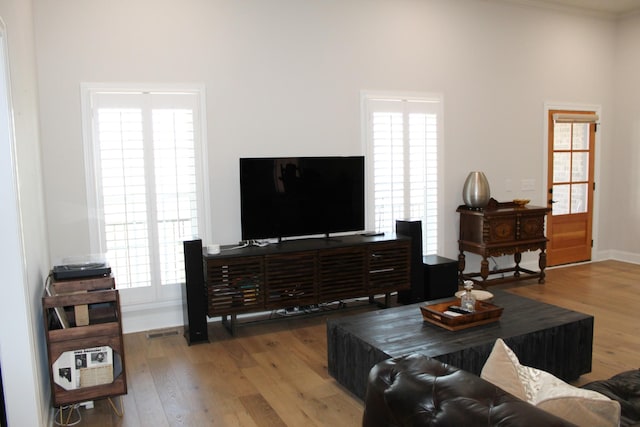 living room featuring visible vents, crown molding, baseboards, and wood finished floors