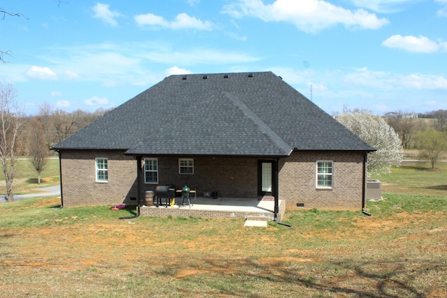 rear view of house with brick siding, a patio, a yard, and roof with shingles