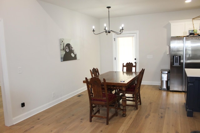 dining space with light wood finished floors, baseboards, and an inviting chandelier