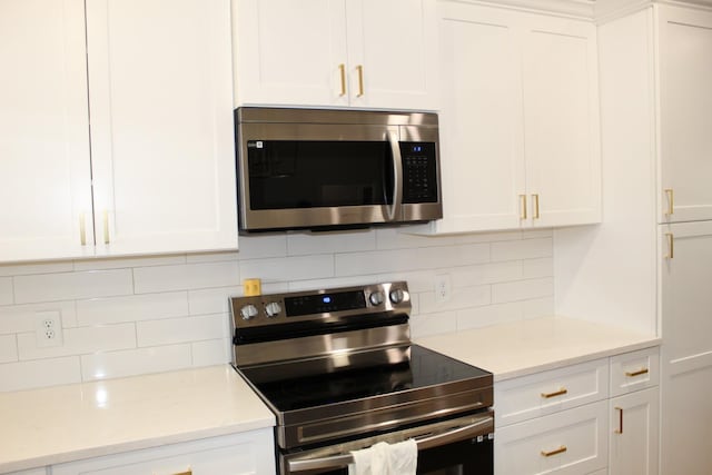 kitchen featuring backsplash, appliances with stainless steel finishes, light countertops, and white cabinetry