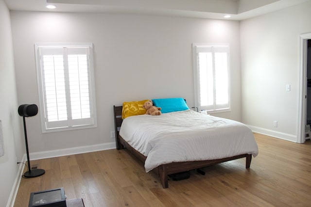 bedroom with multiple windows, baseboards, and hardwood / wood-style floors