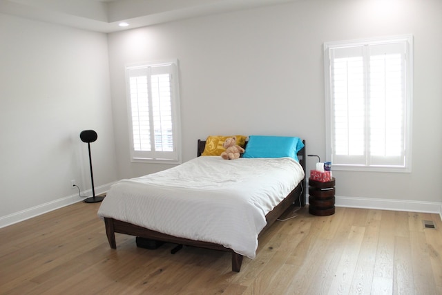 bedroom featuring baseboards, multiple windows, and hardwood / wood-style floors