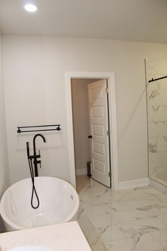 bathroom featuring recessed lighting, a freestanding tub, baseboards, and marble finish floor