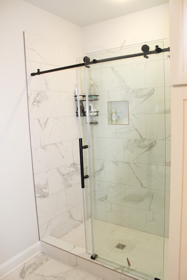 bathroom featuring marble finish floor, a stall shower, and baseboards