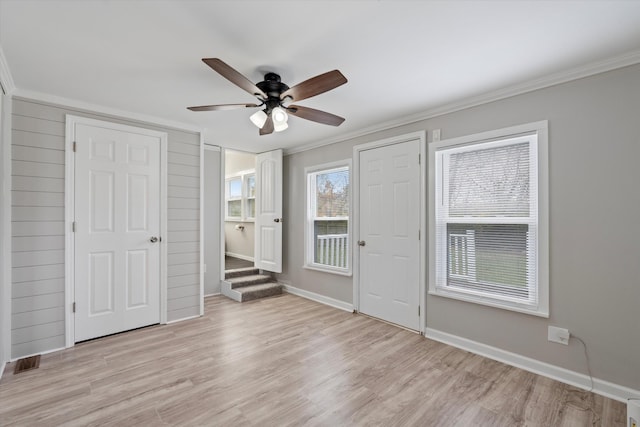 interior space with a ceiling fan, baseboards, visible vents, crown molding, and light wood-type flooring