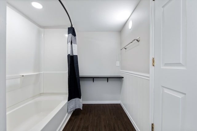 full bath featuring shower / bath combination with curtain, wood finished floors, and a wainscoted wall