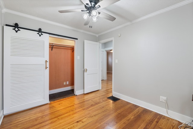 unfurnished bedroom featuring visible vents, baseboards, light wood-style flooring, ornamental molding, and a closet