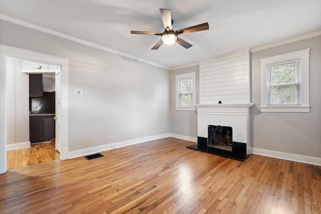 unfurnished living room with crown molding, a ceiling fan, visible vents, and light wood finished floors