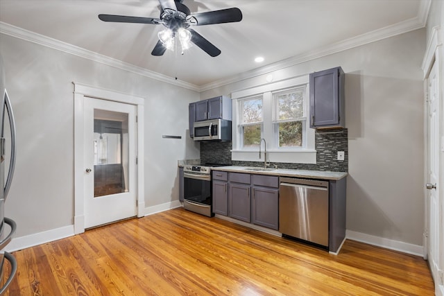 kitchen featuring ceiling fan, gray cabinetry, a sink, appliances with stainless steel finishes, and light wood-type flooring