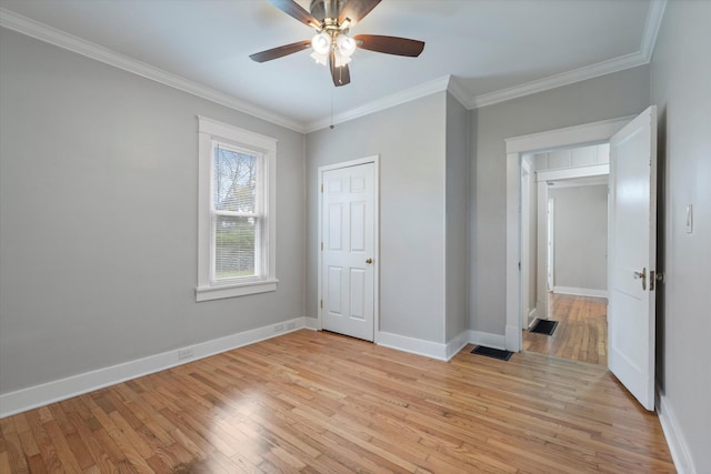 unfurnished bedroom featuring visible vents, light wood-style flooring, ornamental molding, baseboards, and ceiling fan