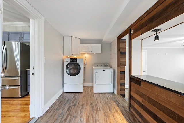 washroom featuring washing machine and clothes dryer, light wood finished floors, and baseboards