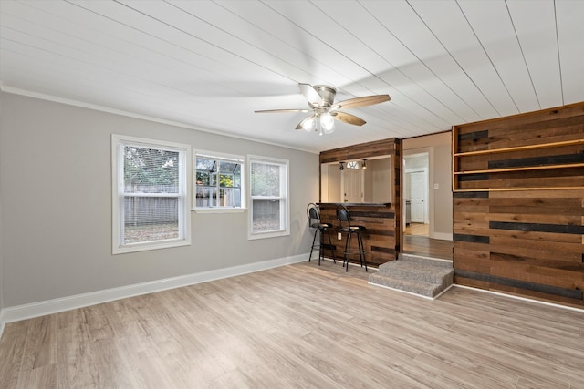 interior space featuring ceiling fan, baseboards, light wood-style flooring, and ornamental molding