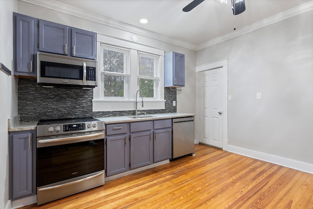 kitchen with ornamental molding, a sink, appliances with stainless steel finishes, baseboards, and ceiling fan