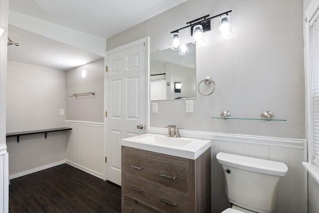 bathroom featuring vanity, toilet, wood finished floors, and a wainscoted wall