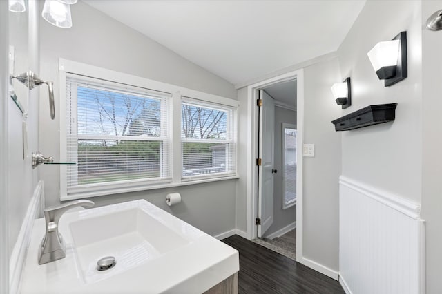 bathroom with wood finished floors, baseboards, and vaulted ceiling