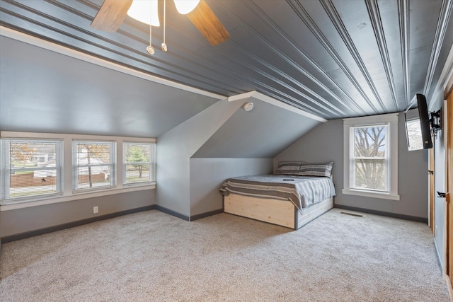 unfurnished bedroom with baseboards, multiple windows, carpet floors, and vaulted ceiling