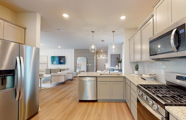 kitchen featuring a sink, light wood-type flooring, appliances with stainless steel finishes, and decorative backsplash