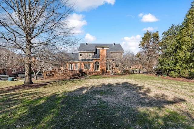 back of house featuring a deck, a lawn, fence, and roof with shingles