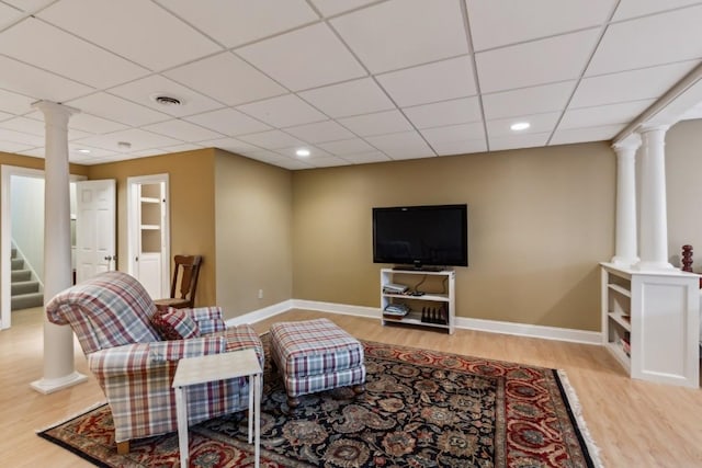 living area featuring stairway, light wood-type flooring, baseboards, and decorative columns