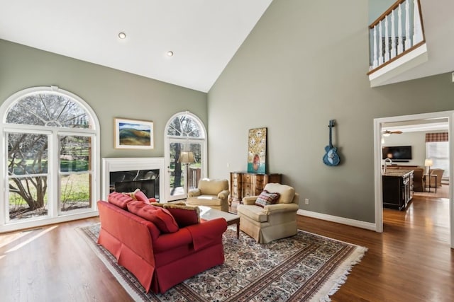 living room with high vaulted ceiling, wood finished floors, recessed lighting, a fireplace, and baseboards