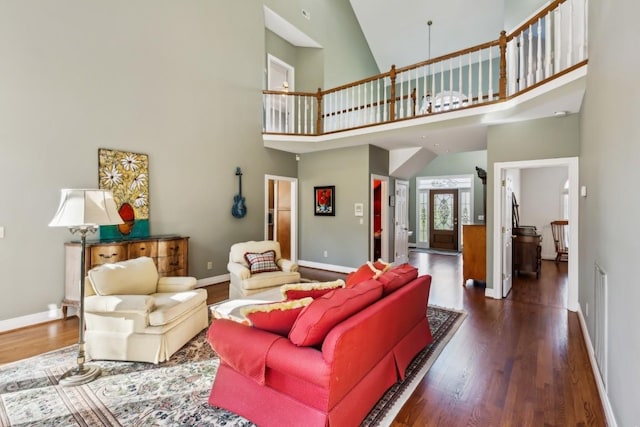 living area with a high ceiling, wood finished floors, and baseboards