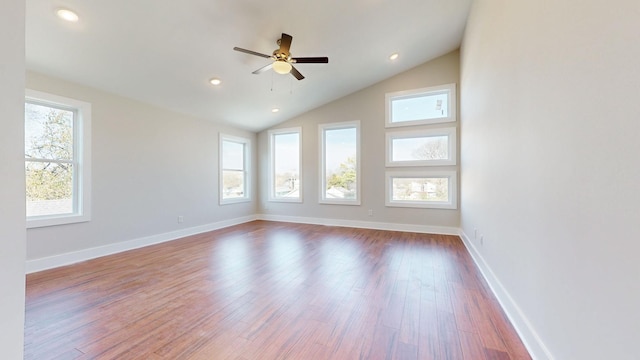 empty room featuring a wealth of natural light, a ceiling fan, lofted ceiling, and wood finished floors