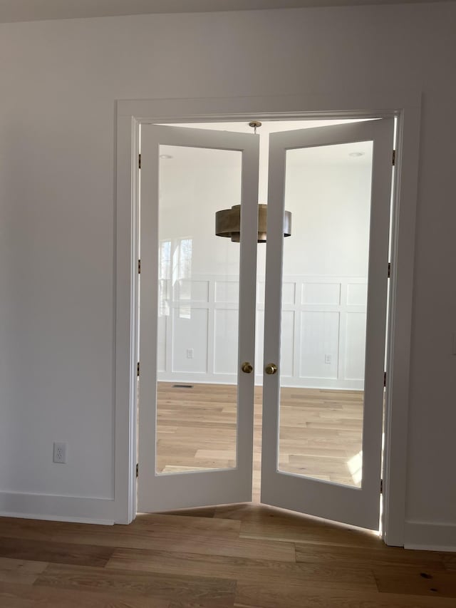 doorway featuring french doors, baseboards, and wood finished floors