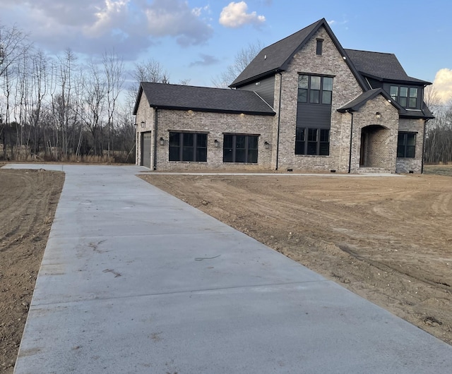 view of front of house with brick siding, an attached garage, driveway, and a shingled roof