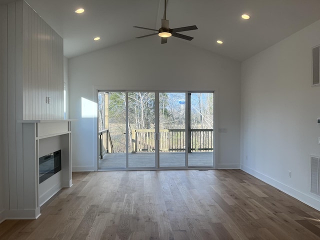 unfurnished living room featuring visible vents, wood finished floors, a glass covered fireplace, baseboards, and ceiling fan