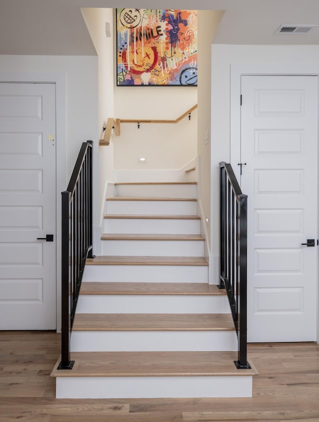 staircase featuring visible vents and wood finished floors