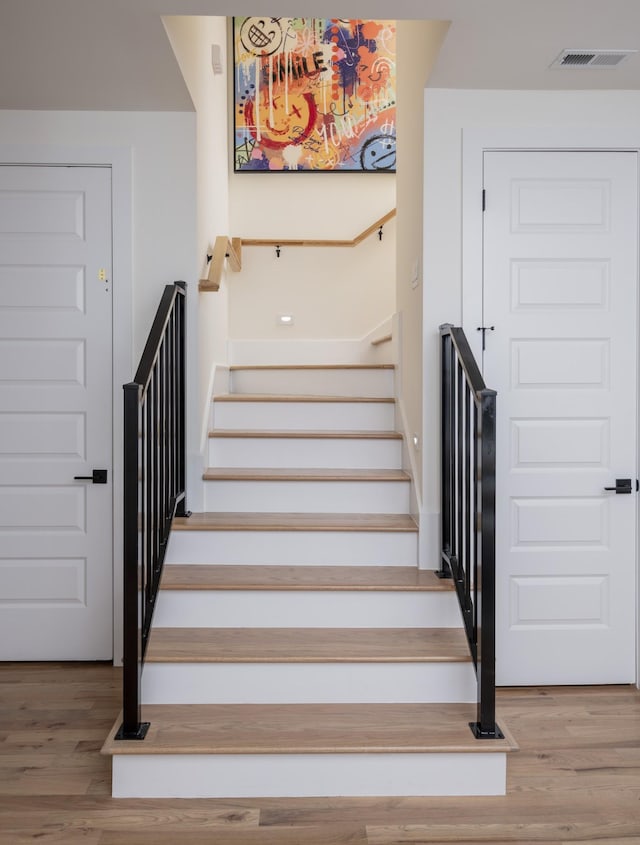 staircase with visible vents and wood finished floors