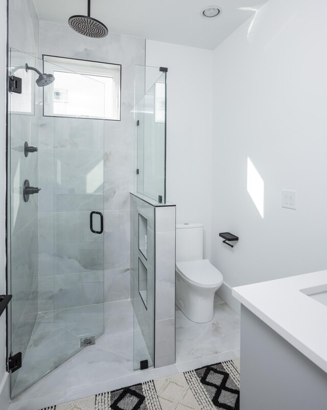 bathroom featuring marble finish floor, a stall shower, toilet, and vanity