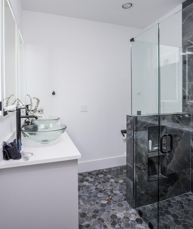 bathroom with double vanity, baseboards, a stall shower, and a sink