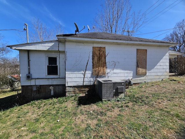 rear view of property featuring central AC unit and a lawn