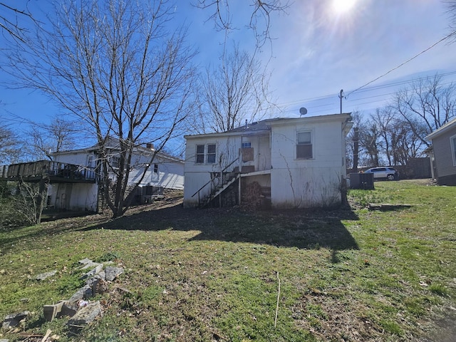 rear view of property with stairs and a yard