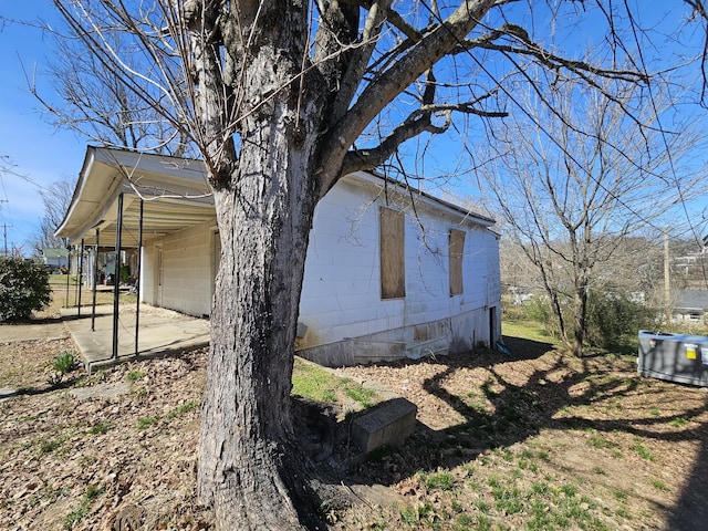 view of side of property with an attached carport and concrete block siding