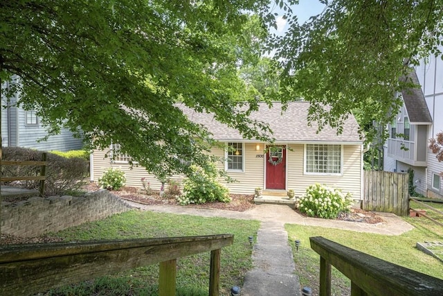 view of front of property featuring a shingled roof, a front yard, and fence