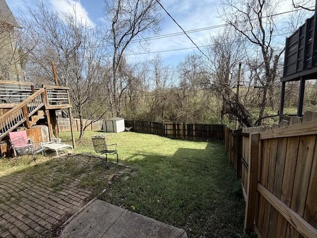 view of yard featuring a storage shed, an outdoor structure, a fenced backyard, and a patio