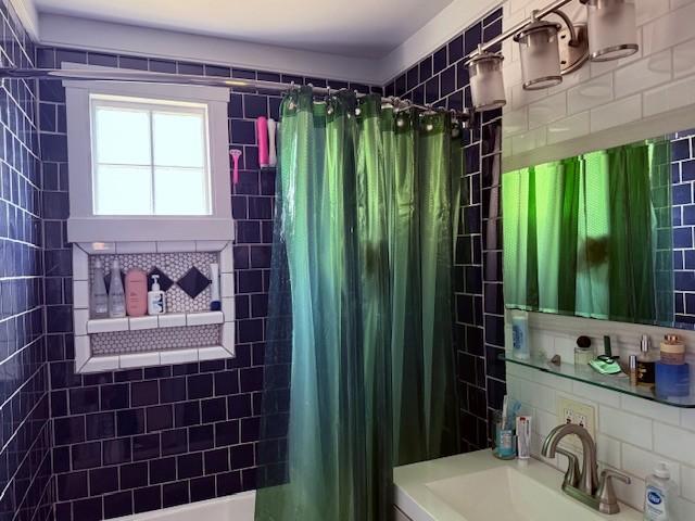 full bath featuring decorative backsplash, shower / bathtub combination with curtain, and a sink