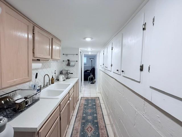 kitchen featuring light countertops, light tile patterned floors, tasteful backsplash, and a sink