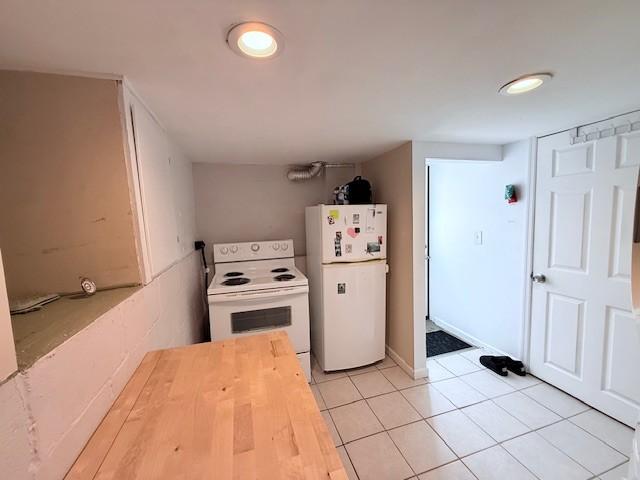 kitchen with light tile patterned floors, white appliances, and wood counters